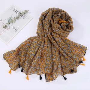 Detail of yellow beach shawl with white shell patterns and black tassel fringe