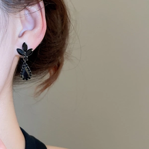 Close-up of vintage black leaf and teardrop crystal earrings worn on a model
