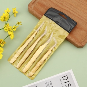 4-piece set of golden eyelash tweezers with plastic protective tips on a desktop