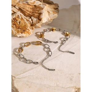 Macro view of two-tone gold and silver chain bracelets on a textured natural stone base