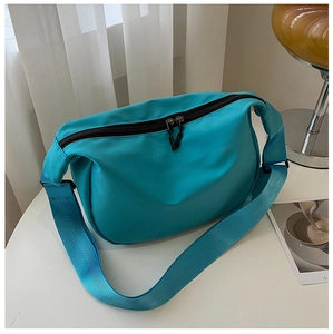 Close-up of stylish lake blue nylon crescent bag with wide woven strap on a table