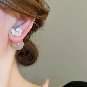 Detail shot of vintage flower stud earring with pearl back and gold center on model ear