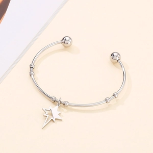 Detail of silver stainless steel open bangle with hollow star charm and bead accents
