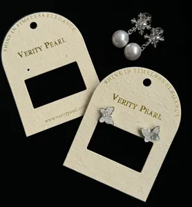 Detailed view of snowflake pearl earrings and butterfly studs on cream jewelry display cards