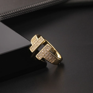 Close-up of golden T-shaped ring featuring sparkling pavé zircon stones on dark background