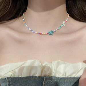 Close-up of a colorful beaded starfish and daisy flower necklace worn on neck