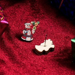Macro detail of cartoon snowman stud earrings with painted wood texture and metal posts