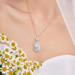 Macro shot of a luxury pear-cut zircon pendant necklace worn with an elegant white dress