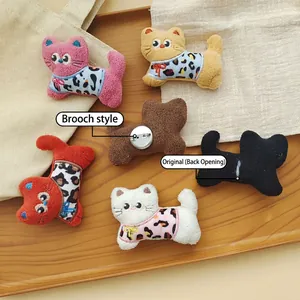 Handmade leopard print cat plush pins in six colors on a wooden tray with a linen background