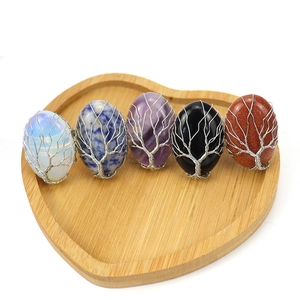 Five pieces of handmade Tree of Life wire wrapped oval crystal rings in a heart wooden tray