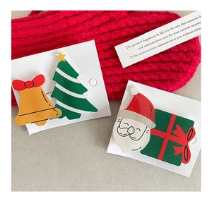 Close-up of Christmas hair clips with Santa, tree, bell and gift box on red knit