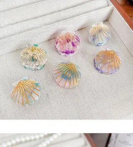 Detail of shell-shaped marble acetate hair clips with fine gold textured lines