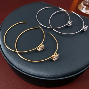 Détail de boucles d'oreilles créoles C en or et argent avec incrustation de zircone cubique