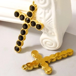 Gold stainless steel cross pendant with black gemstone inlay on a white studio background
