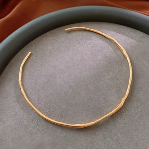 Detail view of wavy gold-plated choker necklace on velvet jewelry display