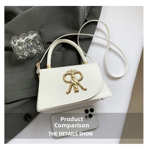 Detail of white leather trapezoid bag with gold metal R logo on gray suit fabric