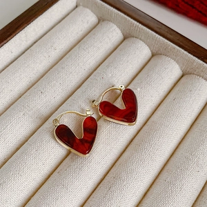 Détail de boucles d'oreilles cœur en émail rouge dans une boîte à bijoux en velours