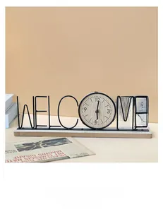 Macro detail of Welcome metal art clock featuring a black iron frame and wooden base