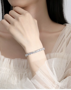 Close-up of a silver tennis bracelet with clear moissanite stones on a woman's wrist