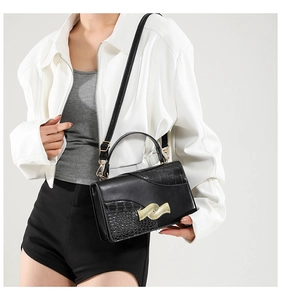 Detail of black crossbody bag with gold wave buckle and mixed faux crocodile texture