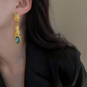 Nahaufnahme von vintage barocken vergoldeten langen ohrringen mit grünem edelstein detail.