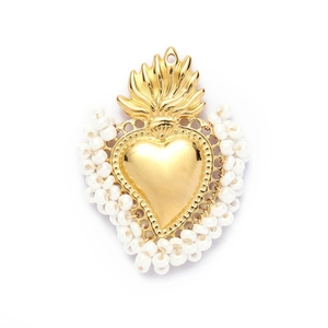 Macro shot of sacred heart pendant with gold metal finish and white bead borders