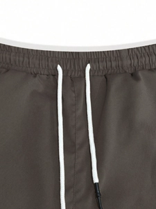 Macro detail of dark grey cargo pants waistband featuring white drawstrings and twill texture
