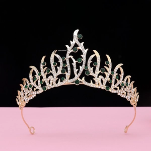 Detailed view of baroque gold crown with emerald green gems and white rhinestones