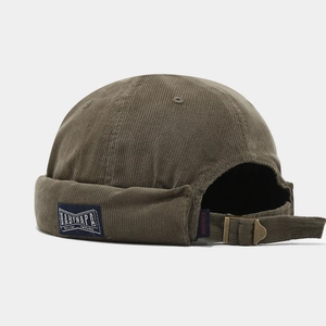 Detail of olive corduroy brimless docker hat showing side woven label and metal buckle