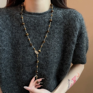 Detail view of long tiger eye bead necklace with a golden zircon leaf pendant on model