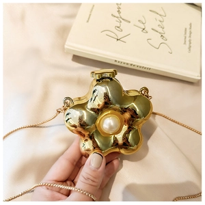 Close-up of golden acrylic flower bag with central pearl and metallic chain detail
