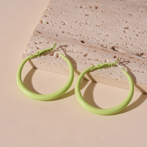 Detail of light green hoop earrings with glossy finish on a natural stone surface