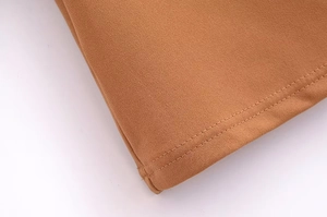 Close-up of brown dress fabric showing fine texture and durable double-needle stitching