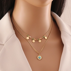 Close-up of double-layered gold necklace with sun pendant and turquoise beads on a model