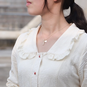 Close-up of a gold MAMA letter pendant necklace with diamonds on a female model