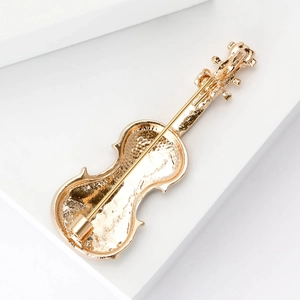 Golden violin brooch made of polished metal shown from the back with safety pin clasp