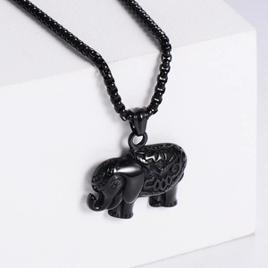 Vintage black elephant pendant necklace with detailed engraving on a white display block