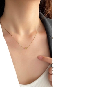 Gold minimalist heart pendant necklace with fine snake chain worn by a woman
