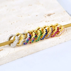 Detailed macro view of colorful baguette-cut cubic zirconia stones on gold huggie earrings