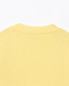 Détail du décolleté d'une robe en tricot jaune avec des boutons étoilés décoratifs