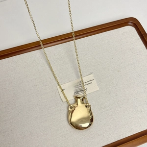 Detail shot of a minimalist gold perfume bottle pendant on a delicate link chain necklace