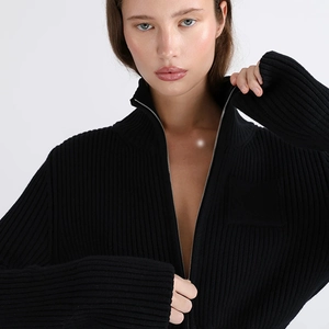 Close-up of ribbed knit texture and front metal zipper on minimalist black sweater