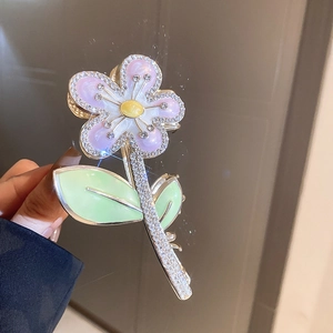 Détail de la pince à cheveux fleurie aux pétales dégradés et strass brillants