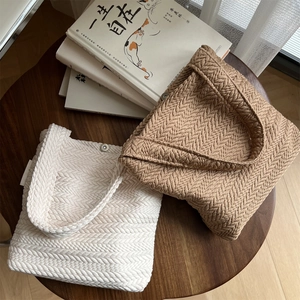 Detail of knit shoulder bags with herringbone texture and magnetic closure on wood
