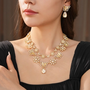 Détails d'un ensemble collier et boucles d'oreilles dorés avec papillons et perles