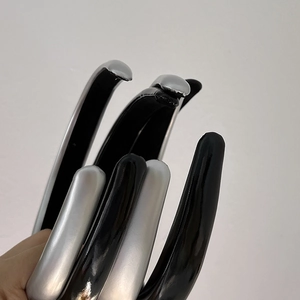 Detail view of glossy black and silver headbands being held in hand for hair styling