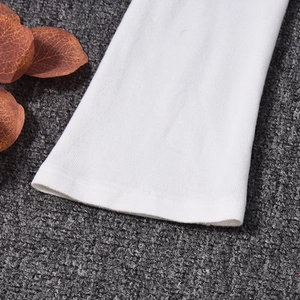 Détail du poignet d'une robe en tricot blanc montrant la texture côtelée du tissu