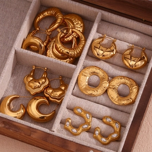 Detailed macro view of 18K gold-plated geometric hoop earrings in a wooden jewelry box