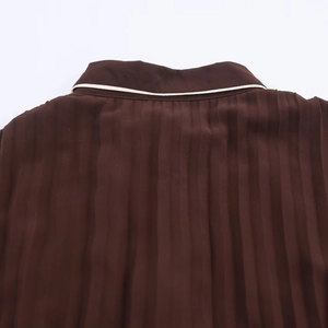 Detail of dark brown pleated midi dress collar with cream contrast piping trim