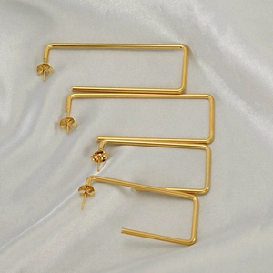 Chic gold geometric C-shaped earrings on grey silk background professional display